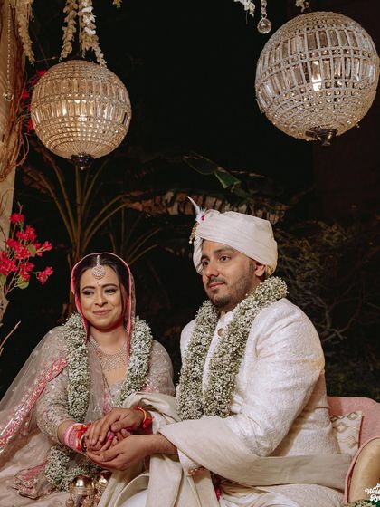 A portrait of the couple during their wedding ceremony, with elegant chandeliers hanging above them.