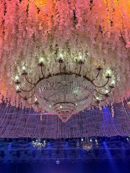 A close-up of a dazzling cascade of crystals and blooms. The combination of a classic crystal chandelier with modern floral and string installations creates a unique and glamorous effect. 💫