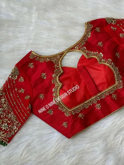 A masterpiece for our bride Madhuri. This classic red bridal blouse is heavily embroidered with zardosi and stone work, featuring a beautiful heart-shaped cutout on the back. The sleeves are a canvas of intricate floral patterns, making it a truly royal piece.