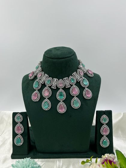 A modern necklace set with large, teardrop-shaped stones in a cascading design. This piece is available in several colors, including pink, green, and red, offering a bold and stylish look.