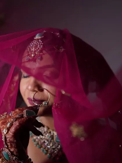 The veil shot is timeless. Here, the bride's face is partially covered by her pink dupatta, creating a soft and romantic portrait that feels intimate.