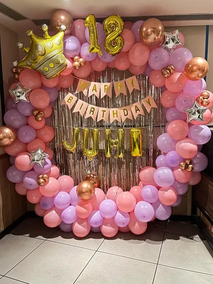 A pink and purple ring decoration for an 18th birthday, with a silver fringe curtain and the name 'JUHI' in foil letters.
