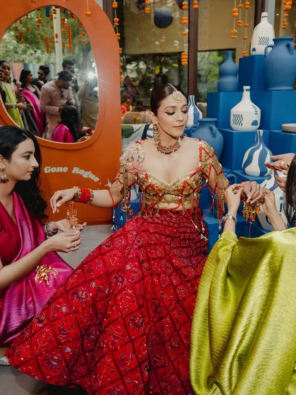 This shot captures the full context of Shweta's Mehendi, surrounded by friends and family. Her makeup looks fresh and vibrant, perfectly suited for a daytime event filled with color and joy.