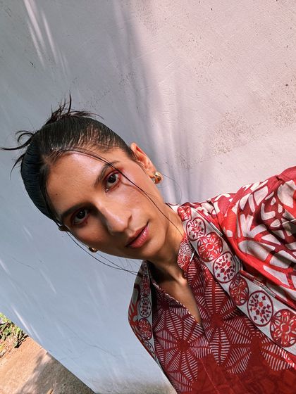 A selfie in a red printed outfit. The messy bun and minimal makeup let the bold color and print do all the talking.