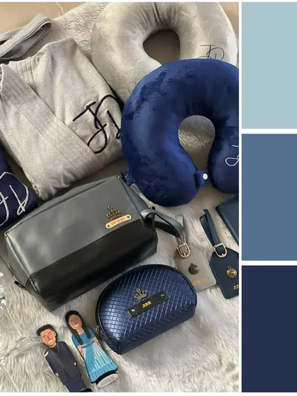 A "Something Blue" themed hamper with personalized travel essentials. This set includes monogrammed robes, a neck pillow, matching pouches, and even custom caricature figures of the couple.