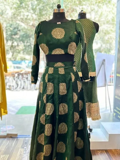 This custom brocade silk ghagra in a rich emerald green showcases a different side of bridal wear. The full-sleeved crop top and flowing skirt feature classic brocade motifs, creating a sophisticated and regal look perfect for a sangeet or reception.