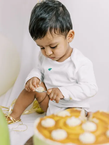 A baby boy carefully inspecting his cake with a spoon. Each child has their own unique approach to a cake smash.