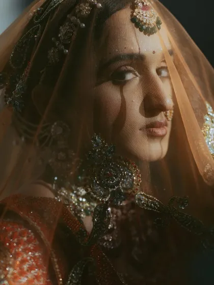 A close-up bridal portrait through her veil. The soft light and shadow create a mysterious and captivating mood, drawing attention to her expressive eyes.