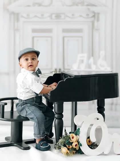 A full view of the 'Little Pianist' setup, showing the elegant studio space and props used to create this classic first birthday portrait.
