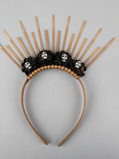 A unique Halloween headband with a golden sunburst design and small skulls.