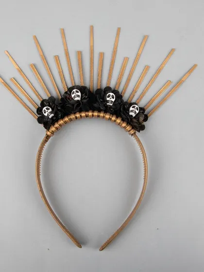 A unique Halloween headband with a golden sunburst design and small skulls.