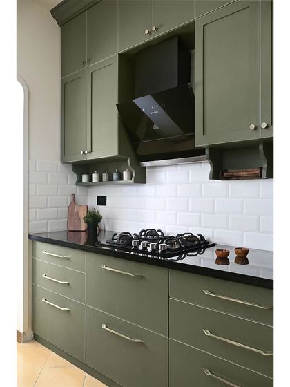 Another view of the deep green classic kitchen. The shaker-style cabinets and black granite countertop create a timeless look, while the subway tile backsplash keeps it feeling fresh and modern.
