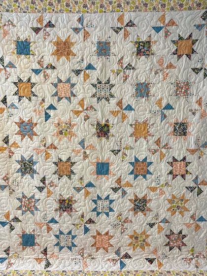 A beautiful quilt featuring a mix of star and pinwheel blocks in a soft, peachy color palette.