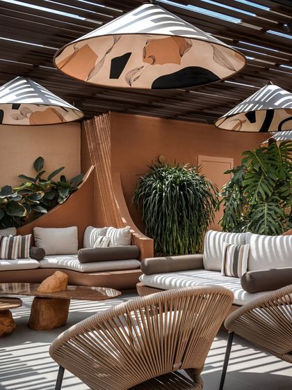 The combination of woven chairs, plush cushions, and stone tables creates a rich material palette. Every element is chosen for its texture, durability, and contribution to the overall aesthetic.