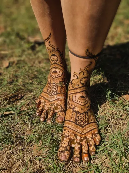 A beautiful shot of bridal feet mehendi in a natural outdoor setting, highlighting the rich color of the henna.