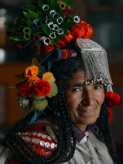 A beautifully lit portrait of a Brokpa woman. The details of her traditional silver headdress and coin-adorned clothing are highlighted, showcasing the craftsmanship of her culture.