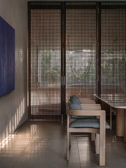 The dining area, with its slatted wooden screens that cast beautiful, linear shadows across the room. The minimalist chairs and table keep the focus on the light and the view outside.