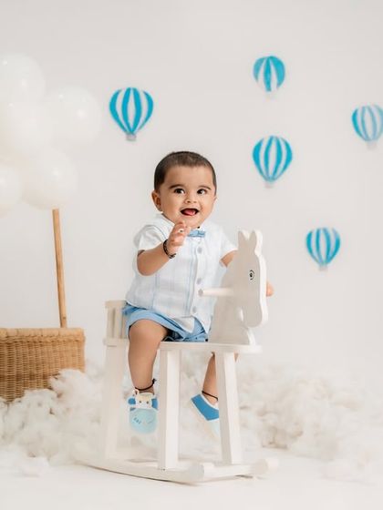 A clean and airy hot air balloon theme. This toddler is riding a rocking horse among the clouds, creating a light and dreamy atmosphere.