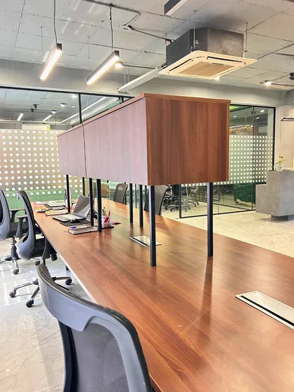 The open-plan workstation area is designed for functionality. Custom overhead storage units in a warm wood finish provide ample space while maintaining an open and collaborative environment.