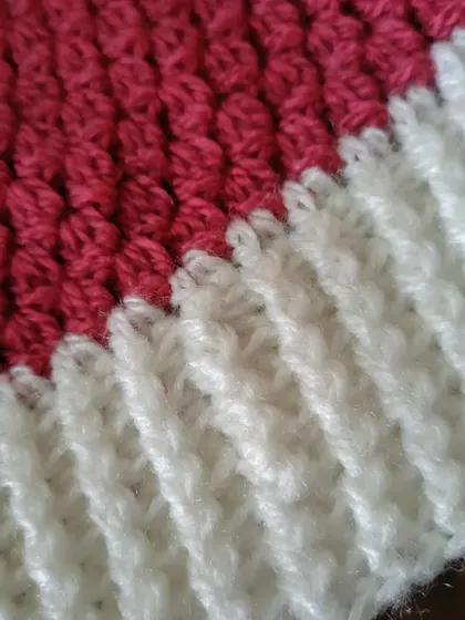 A close-up showing the contrast between the textured cluster stitch body and the neat lines of the front-post ribbed brim.
