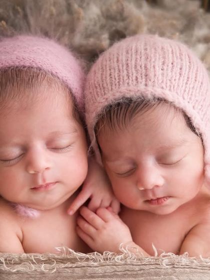 Wrapped in pink and sleeping soundly. These newborn twins look so cozy and content in their matching pink bonnets, a classic and adorable twin portrait.