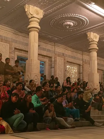 Candid shots of the priests and the large crowd of devotees during the Maha Aarti at JK Temple, capturing the community and shared experience of the event.