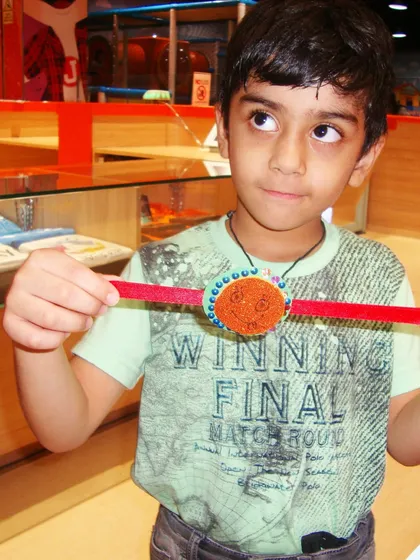 A boy proudly holds up the rakhi he crafted himself during our special Raksha Bandhan event.