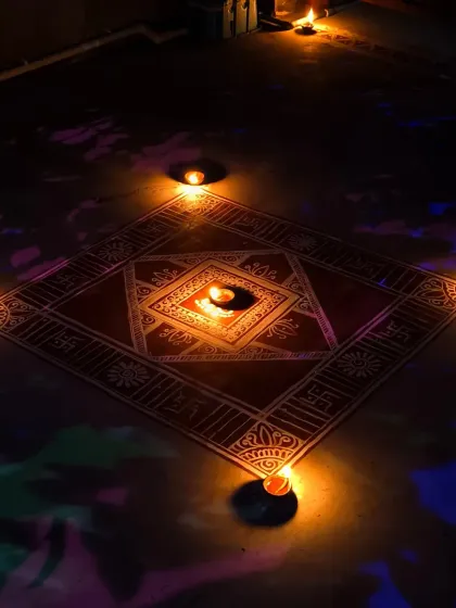 The traditional floor art is fully illuminated by multiple diyas, creating a warm and sacred ambiance. This is the final look, perfect for welcoming light and blessings during Diwali.