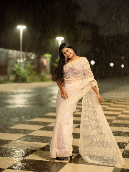 A joyful, dynamic pose in the rain. Her pose and the sweep of the saree create a sense of celebration and movement.