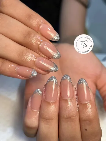 A glamorous twist on the French manicure. This design features a classic nude base with sparkling silver glitter tips for a touch of party-ready glam.
