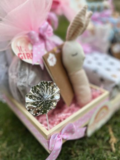 Details from the hanger hamper, including a soft bunny rattle and a silver decorative leaf, adding texture and charm to the overall display.
