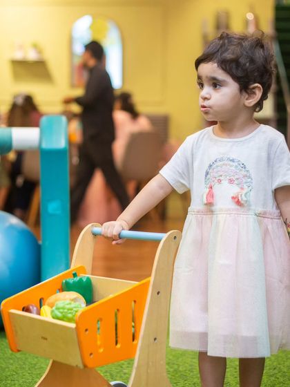 Time for some grocery shopping! This little girl pushes her cart filled with play food, learning through imaginative role-play.