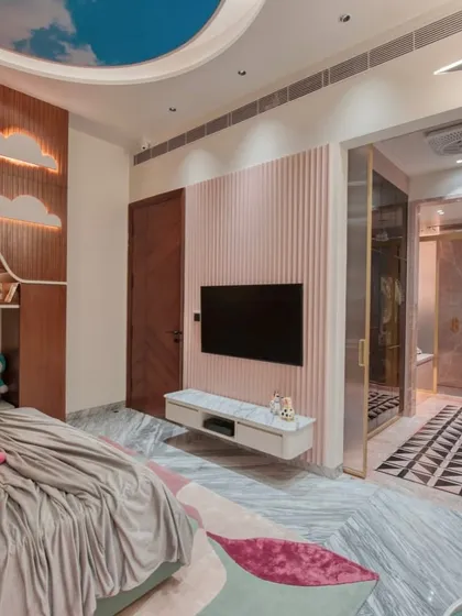 Another view of the kid's bedroom, showing the fluted pink accent wall with a mounted TV and a glimpse into the walk-in closet.