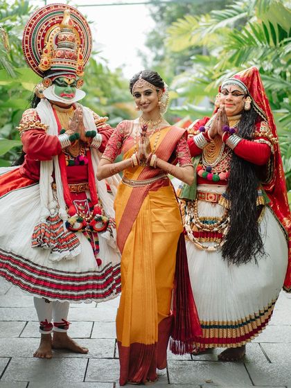 A stunning portrait of a Kerala bride flanked by two Kathakali dancers. This image is a beautiful fusion of bridal elegance and the rich cultural heritage of Kerala.