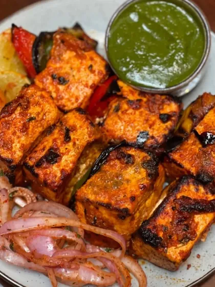 You can't go wrong with a classic Paneer Tikka. I marinate soft cubes of paneer in a blend of yogurt and spices, then grill them with peppers and onions until they have the perfect char. It's served with our signature mint chutney and sliced onions.