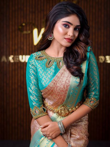 This model is wearing a unique beige and teal saree. The drape is styled to highlight the unusual color combination and the intricate blouse neckline.