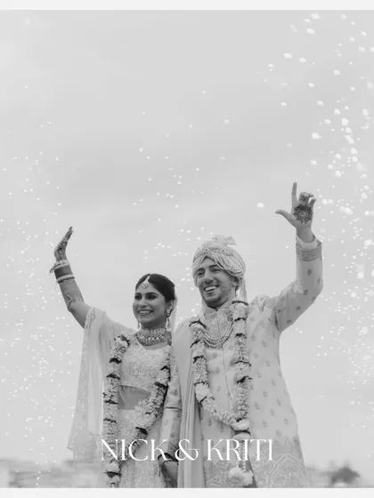 A joyous black and white photo of Nick and Kriti celebrating as newlyweds, surrounded by a shower of sparkles. Their triumphant gestures capture the pure happiness of the moment.
