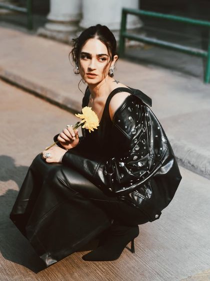 Kavya Trehan holding a single yellow flower. This portrait combines an edgy look with a touch of softness, creating a beautiful juxtaposition.