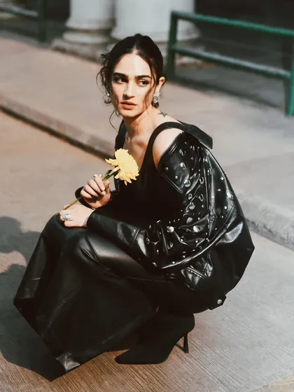 Kavya Trehan holding a single yellow flower. This portrait combines an edgy look with a touch of softness, creating a beautiful juxtaposition.