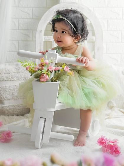 Surrounded by flowers and light, this little one is the star of her first birthday shoot. The white tricycle and soft decor create a dreamy, beautiful scene.