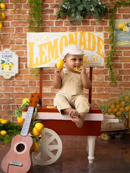 Taking a break to sample the goods. This little one is enjoying a lemon at his stand, creating an adorable and funny moment.