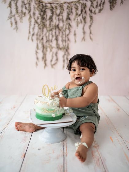 Success! A happy baby enjoying his cake during a fun and messy cake smash photoshoot.