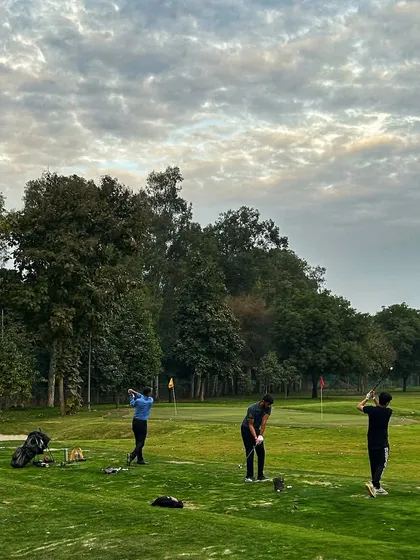 A group of golfers practices under a dramatic, cloudy sky, adding a moody vibe to their session.