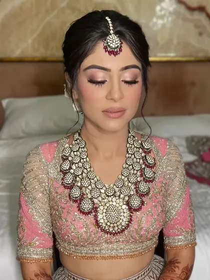 A bride with her eyes closed, showcasing her makeup and soft updo. This hairstyle is perfect for a bride who wants an elegant but not overly severe look.
