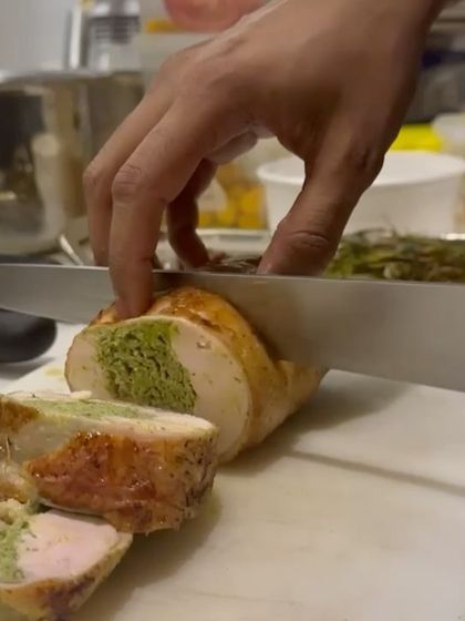 Slicing a Ballotine of Chicken, revealing the vibrant green farce inside. This cross-section shows the technique and care in its construction.