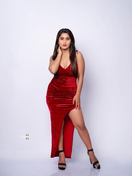 A full-length shot of a model in a stunning red velvet gown. The studio lighting is used to highlight the rich texture of the fabric and create a powerful, glamorous statement.