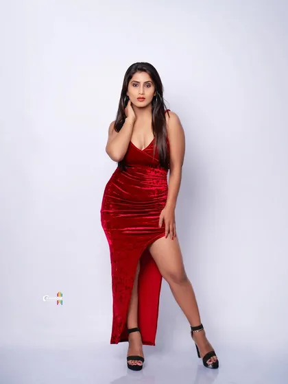 A full-length shot of a model in a stunning red velvet gown. The studio lighting is used to highlight the rich texture of the fabric and create a powerful, glamorous statement.