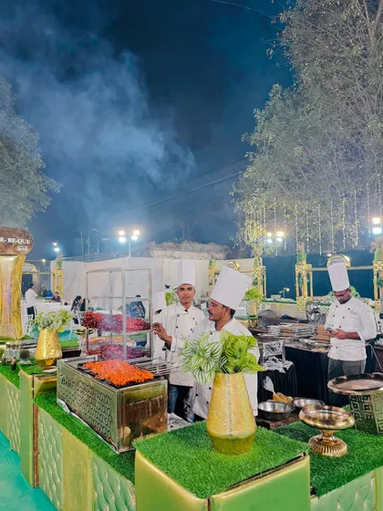 A wider view of the bustling barbecue station, with chefs grilling, smoke rising, and a variety of kebabs on display.