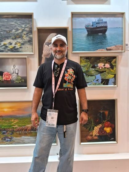 The artist behind the realist paintings, standing proudly with his collection at World Art Dubai.