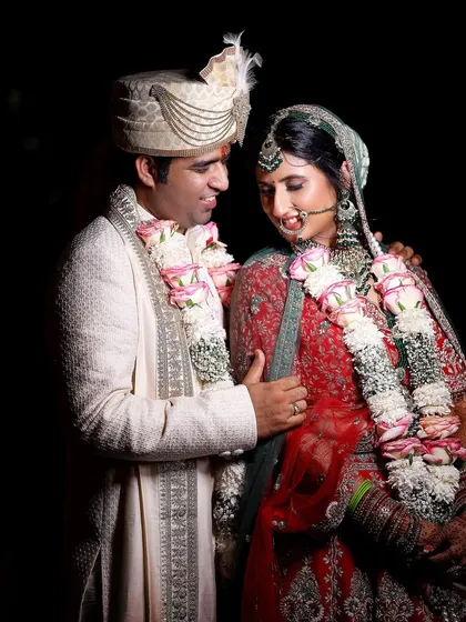 An intimate, candid shot of the couple sharing a quiet moment amidst the wedding celebrations. The dark background makes their love shine even brighter.